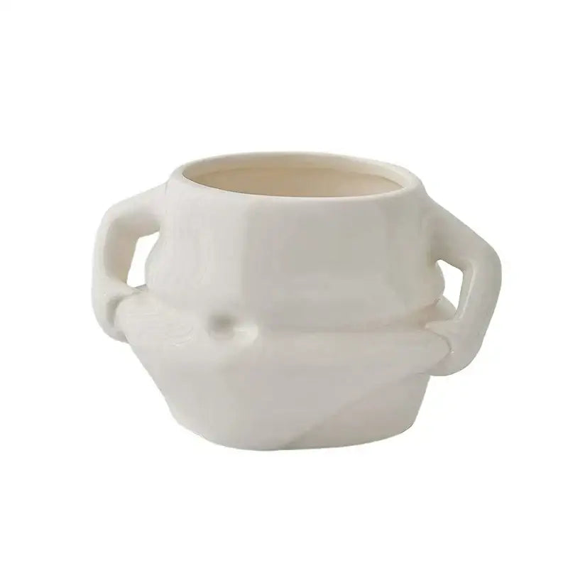 Cream-colored ceramic planter with sculpted handles and geometric design paired with festive white santa claus ceramic mug set