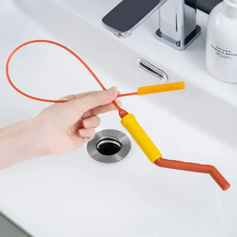 Flexible orange and yellow drain cleaner brush with textured brush head for kitchen clog remover and drain cleaning tasks
