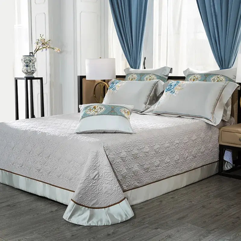 Light gray quilted bedspread with subtle texture and ruffled hem trimmed by brown in floral 200s embroidered egyptian cotton bedding set