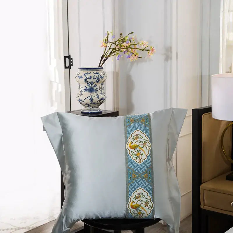 Light blue satin pillow with vertical embroidered band of yellow birds on teal from floral 200s embroidered egyptian cotton bedding set