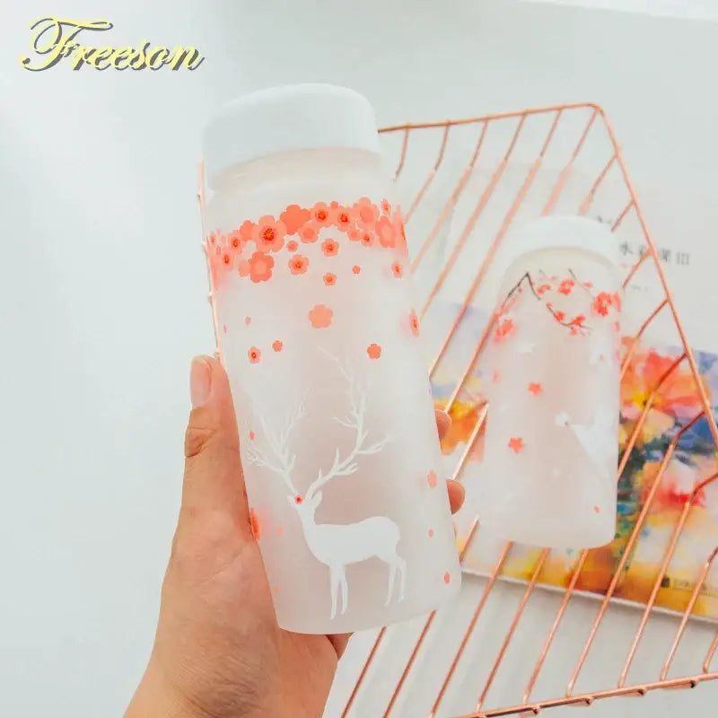 Translucent frosted glass water bottle with white lid featuring pink floral pattern and white deer silhouette design