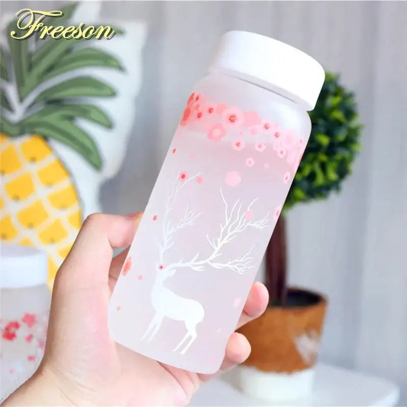 A translucent pink frosted glass water bottle with white lid and delicate white deer and floral decals for kitchen use
