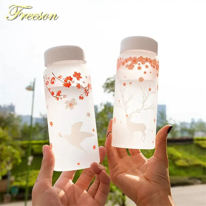 Floral and elk frosted glass water bottle set with white lids featuring cherry blossoms and deer designs