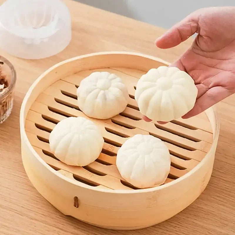 A hand holds a white flower-shaped steamed bun made using a floral baozi mold diy dumpling maker over a bamboo basket