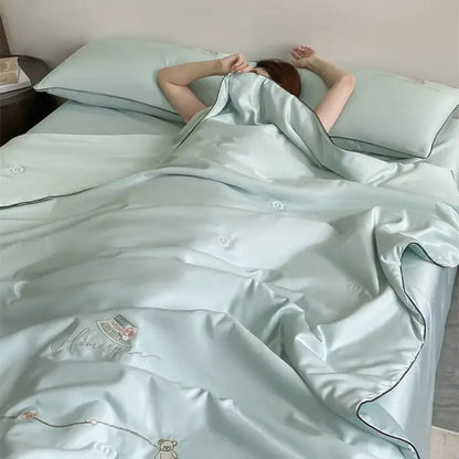 Light blue satin duvet set with subtle embroidery and black piping in a floral bear cream and gold summer blanket set