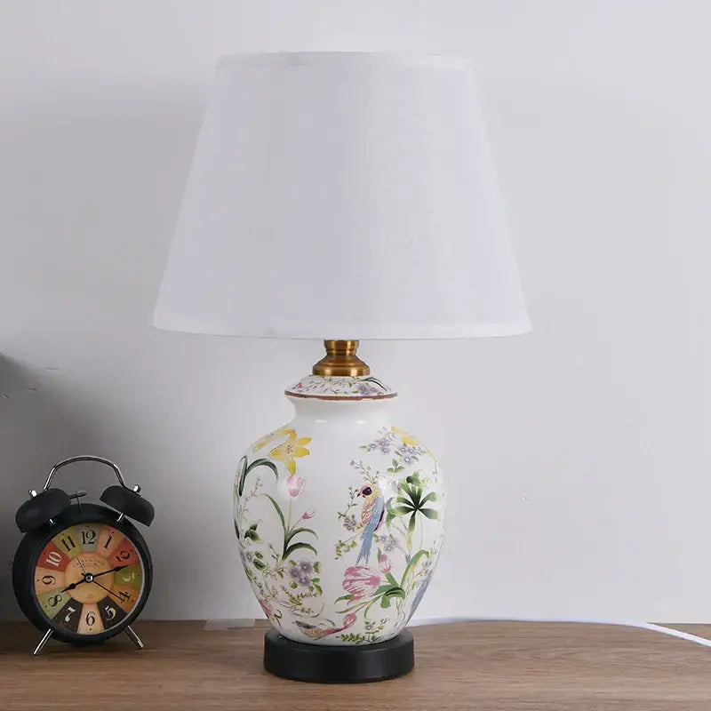 White ceramic table lamp with colorful floral and bird hand-painted design topped with 30cm white fabric lampshade