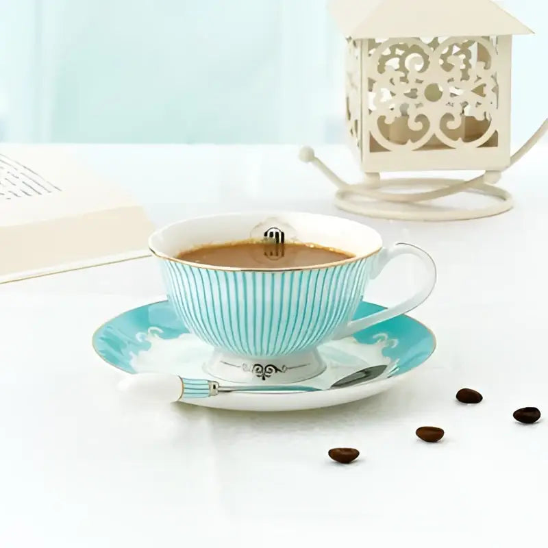 A delicate turquoise and white striped bone china tea cup and saucer with gold trim and silver-toned emblem