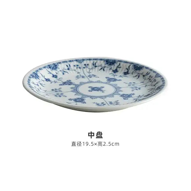 A white ceramic dining plate with delicate blue floral patterns from a floral blue and white ceramic dining set