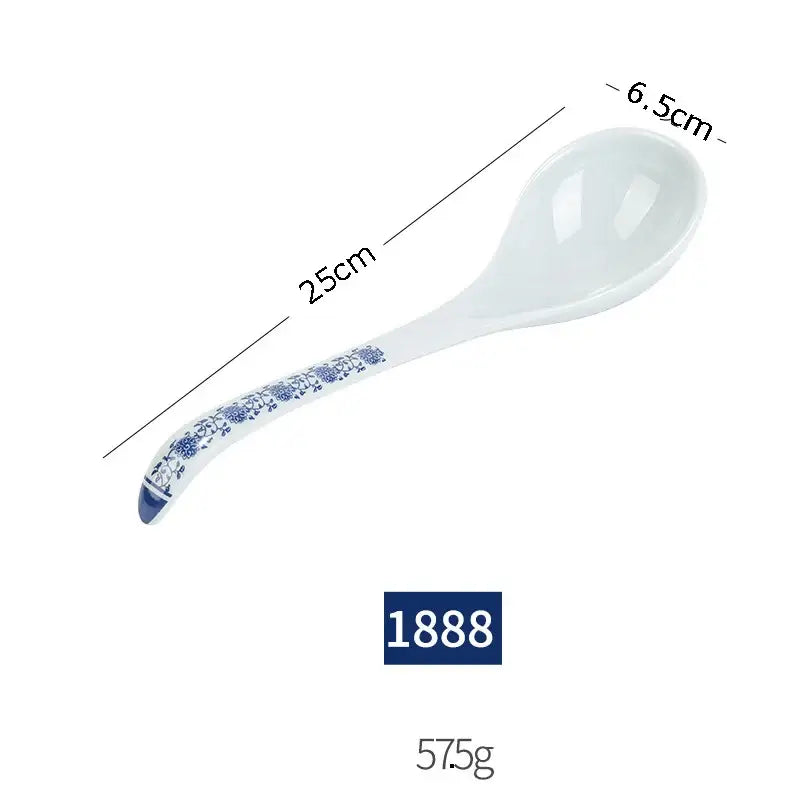 A white imitation porcelain soup spoon with blue floral handle from a floral blue and white imitation porcelain dinner set
