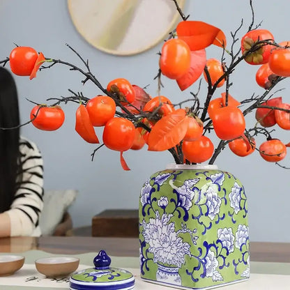 A green ceramic floral blue white porcelain general jar holding orange persimmons for living room decorbites decor