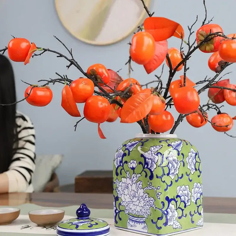 A green ceramic floral blue white porcelain general jar holding orange persimmons for living room decorbites decor