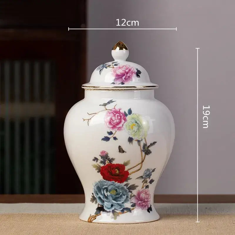 A white porcelain tea pot storage container with gold-trimmed lid and hand-painted floral designs in pink, red, blue, and yellow