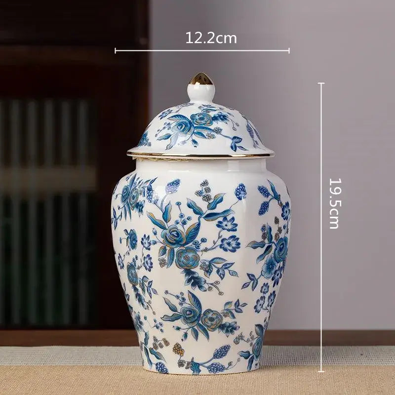 White porcelain tea pot storage container with blue floral pattern and gold trimmed lid featuring rose and leaf designs