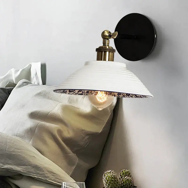 White ceramic wall lamp with brass base black backplate and ornate blue white porcelain floral interior decorbites design