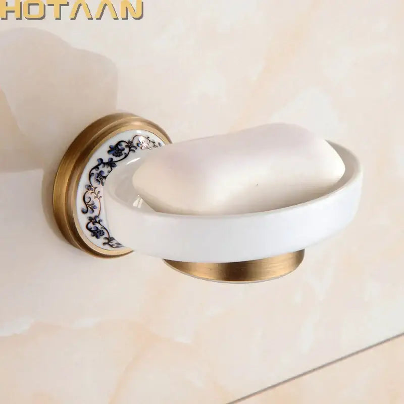 Floral brass soap holder with white ceramic dish featuring blue floral patterns and gold-toned metal accents mounted on wall