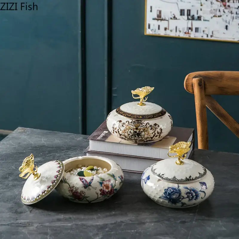 Three ornate floral ceramic storage jars with gold butterfly finials and decorbites dragonfly lid ceramic design