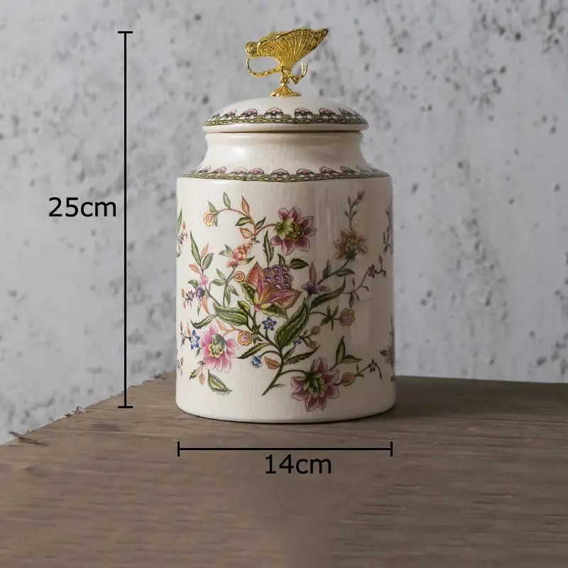 Cream-colored ceramic storage jar with intricate floral patterns and a golden decorbites dragonfly lid for jewelry storage