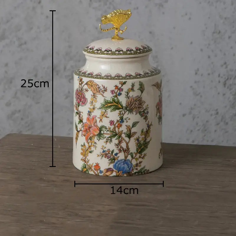 A cream-colored ceramic storage jar with vibrant floral pattern and ornate golden dragonfly lid by Decorbites