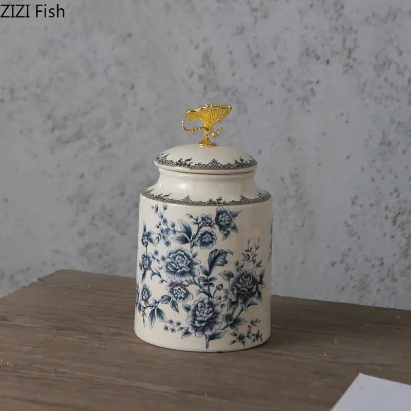 Cream-colored ceramic storage jar with blue floral patterns and gold-toned decorbites dragonfly lid for jewelry storage