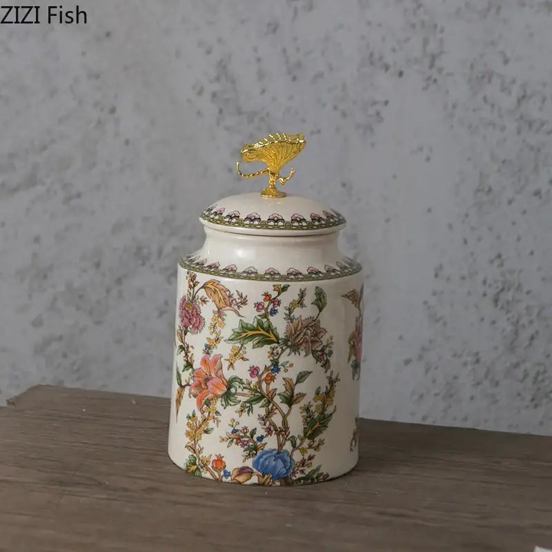 Floral ceramic storage jar with white body, colorful patterns, and gold-toned decorbites dragonfly lid finial