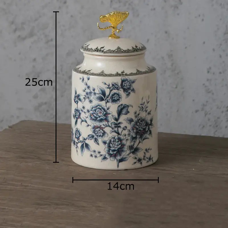 A white ceramic storage jar with blue floral patterns and a gold decorbites dragonfly lid for bedroom use