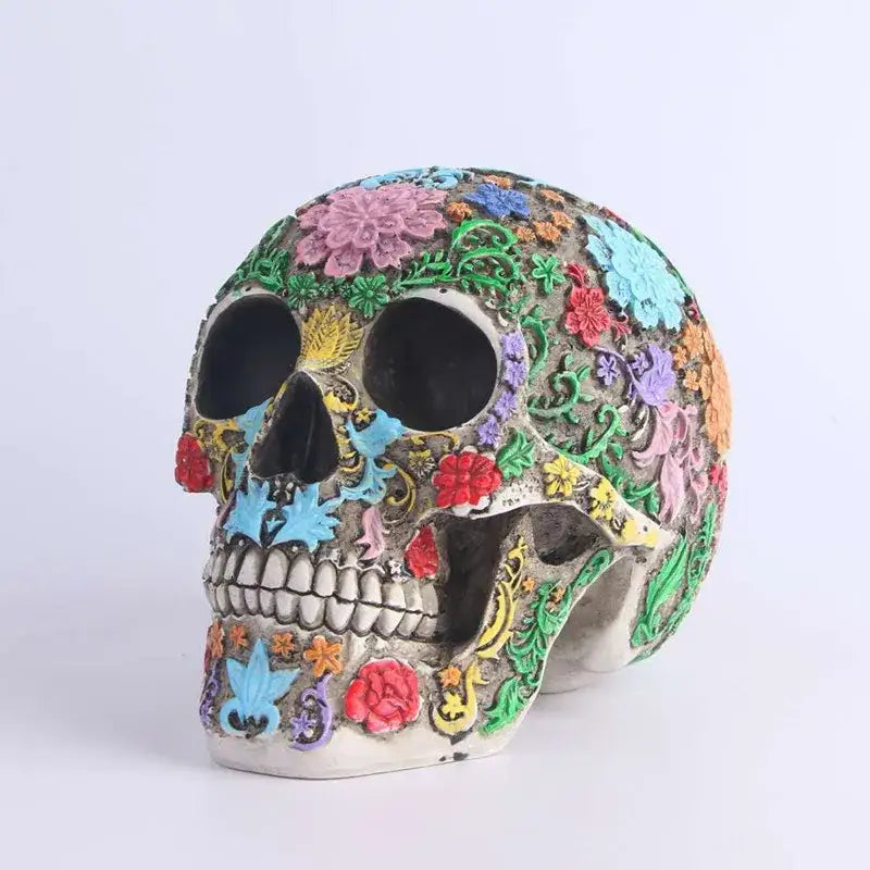 A vibrantly decorated sugar skull ornament with pink blue red green and yellow floral patterns on an off-white base