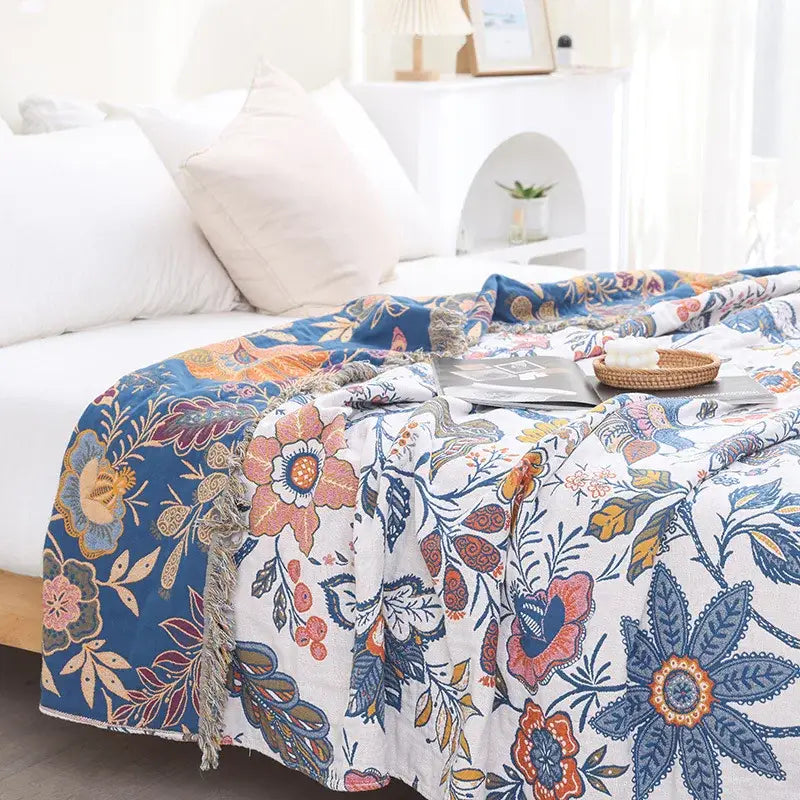 Floral cotton bohemian throw blanket with vibrant floral pattern in blue pink orange green on white with fringed edges