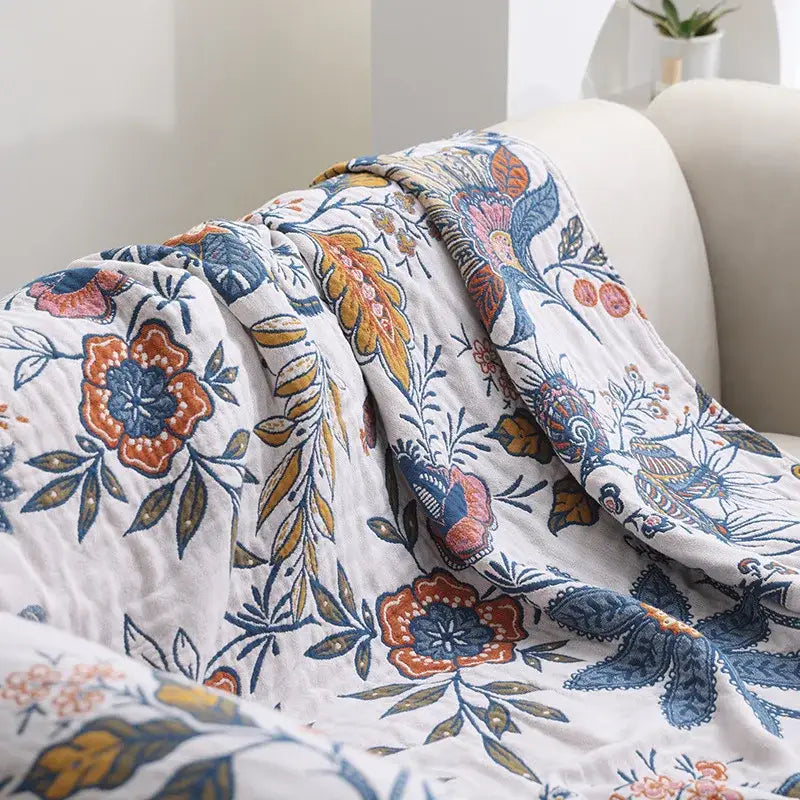 A double cotton bohemian throw blanket with white quilted fabric and vibrant orange blue mustard floral pattern