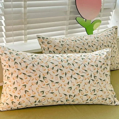 Rectangular pillowcases with a delicate peach and green floral pattern on a cream cotton quilt cover set