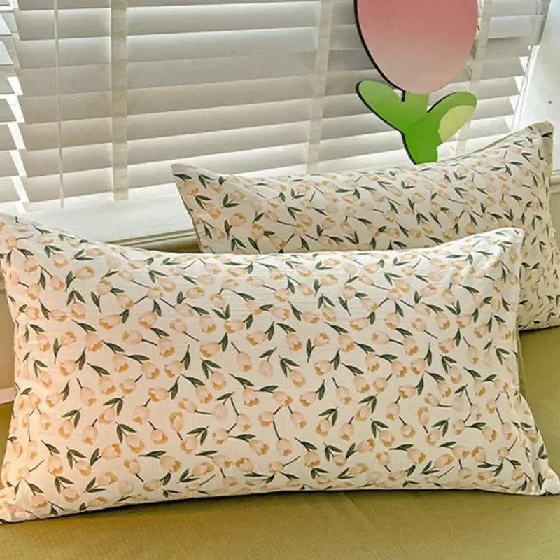 Rectangular pillowcases with a delicate peach and green floral pattern on a cream cotton quilt cover set