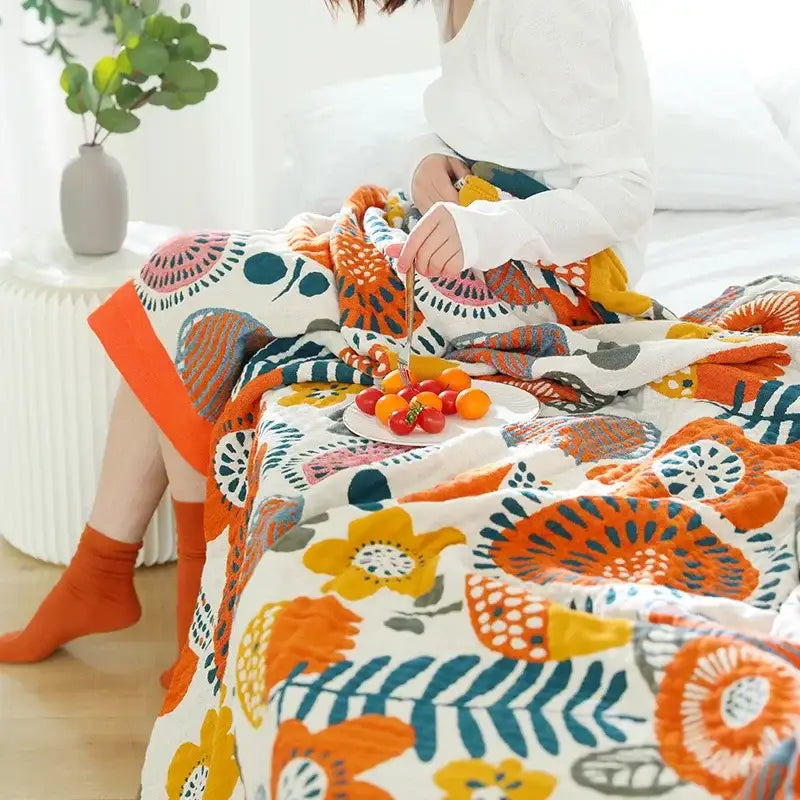 A cozy white double gauze cotton summer blanket with vibrant orange yellow and teal floral pattern for bedroom decor