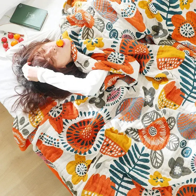 A cozy white quilted double gauze cotton summer blanket with vibrant orange yellow and teal floral pattern