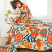 Cozy cream-colored double gauze cotton summer blanket with vibrant oversized orange, yellow, and teal floral pattern