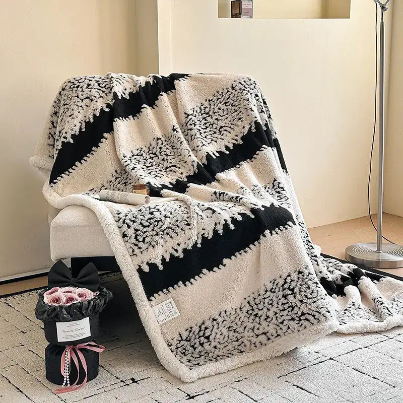 Black and cream jacquard lamb wool blanket with textured floral design draped over armchair for living room throw