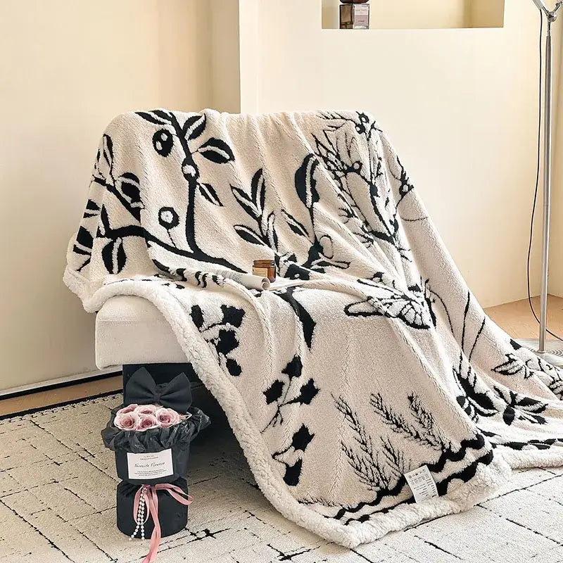 Cream-colored jacquard lamb wool blanket with black botanical embroidery ideal as a living room throw