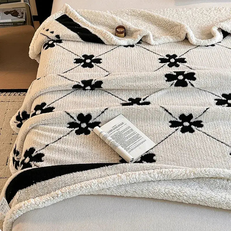 A cozy cream jacquard lamb wool blanket with black floral pattern and soft textured edges for living room throw