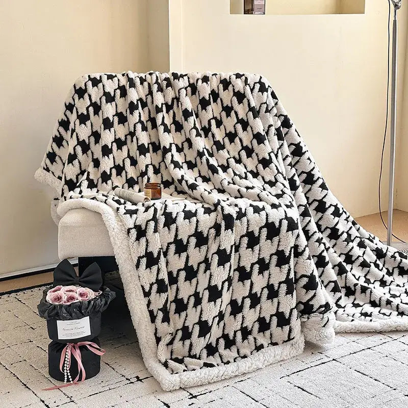 A plush black and white houndstooth jacquard lamb wool blanket with soft fluffy texture for living room use