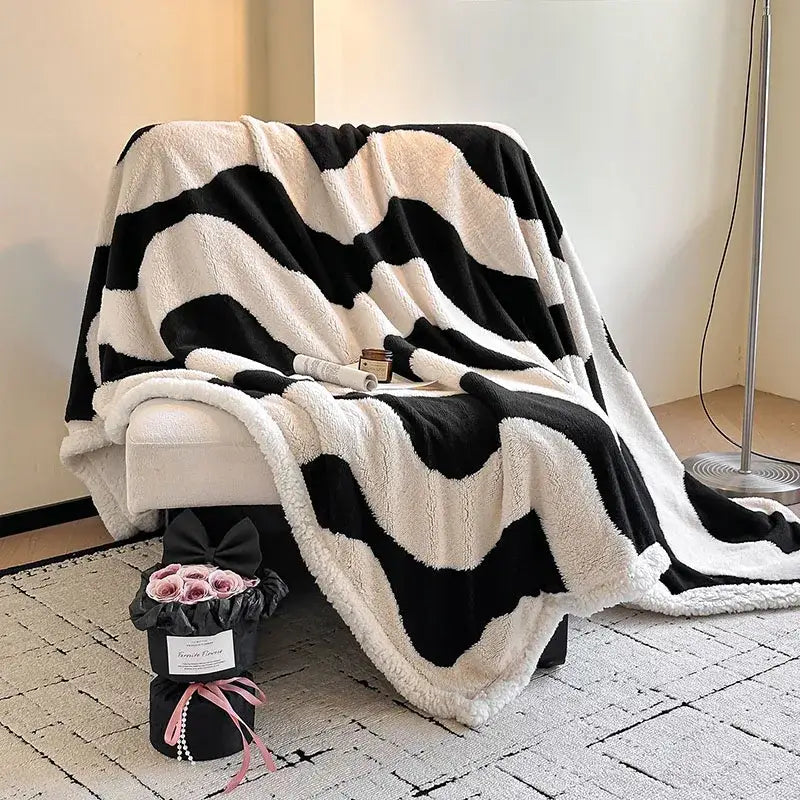 A black and white zigzag jacquard lamb wool blanket draped over a chair for living room use