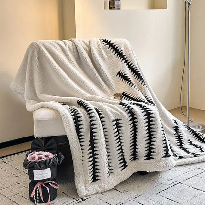 A plush white and black floral cream jacquard lamb wool blanket draped over an armchair with a soft textured surface
