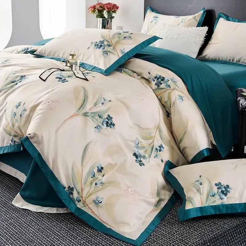 Cream-colored satin egyptian cotton bedding set with blue floral embroidery and teal piping for elegant bedroom decor