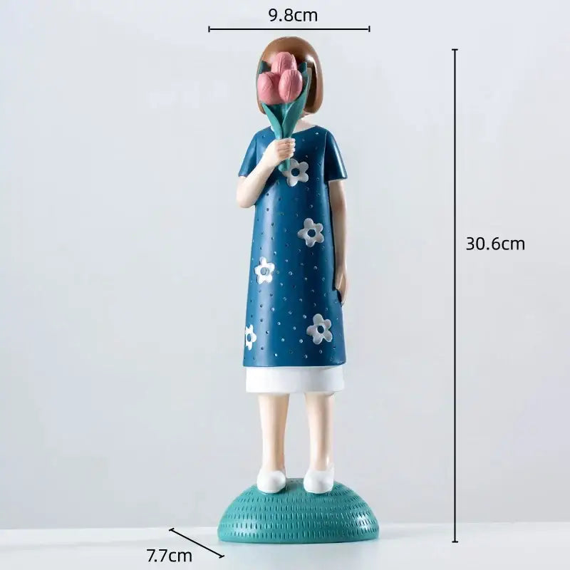 A blue resin figure sculpture of a girl in a floral dress holding pink tulips on a textured teal base for living room decor