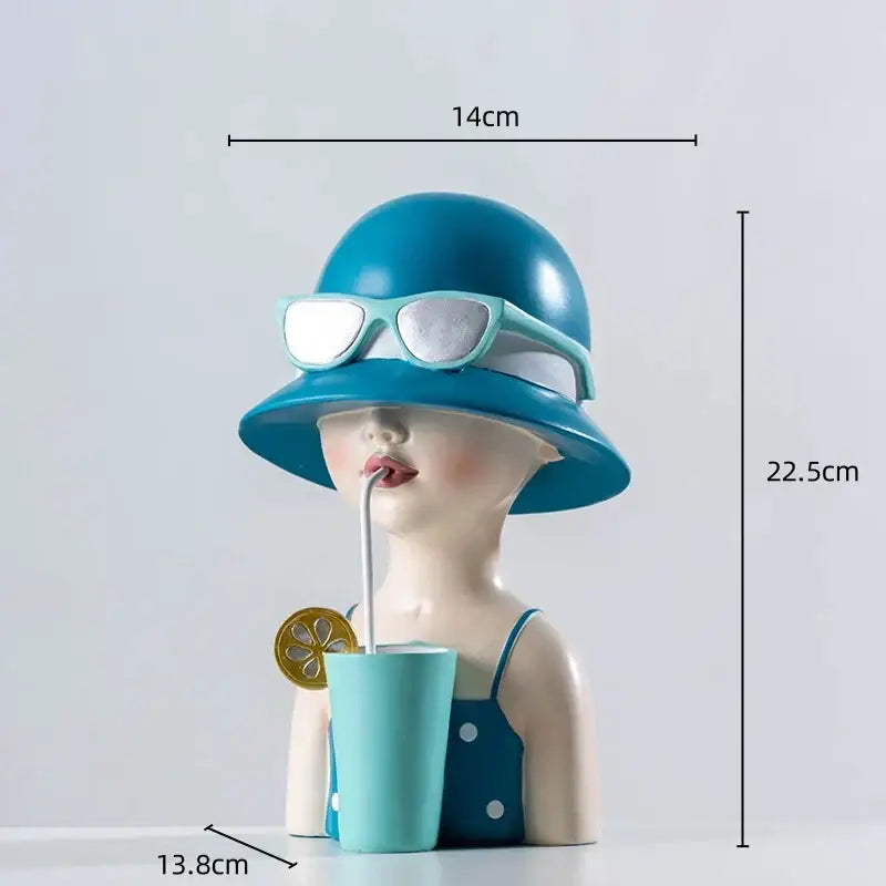 A charming resin figure sculpture of a woman with a blue hat and sunglasses sipping from a turquoise cup