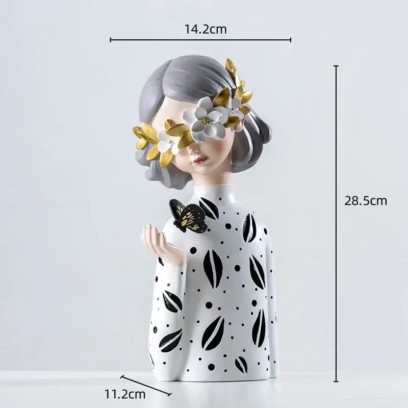 A delicate resin figure sculpture of a girl with a floral crown and black butterfly in white and gold tones for decor