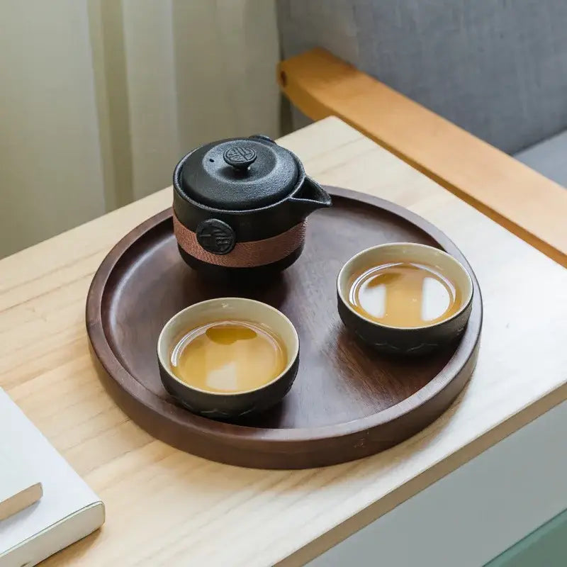 Floral embossed black pottery tea set with decorbites black pottery teapot and cups on dark wooden tray for dining room
