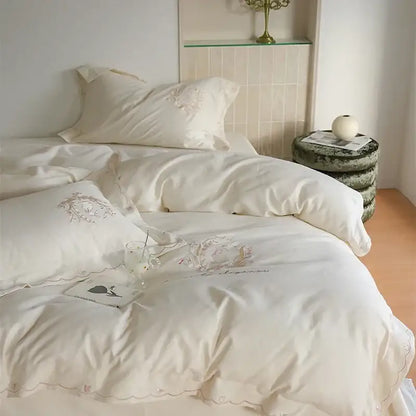 Cream-colored satin duvet cover set with delicate floral embroidery and scalloped edges for elegant bedroom decor