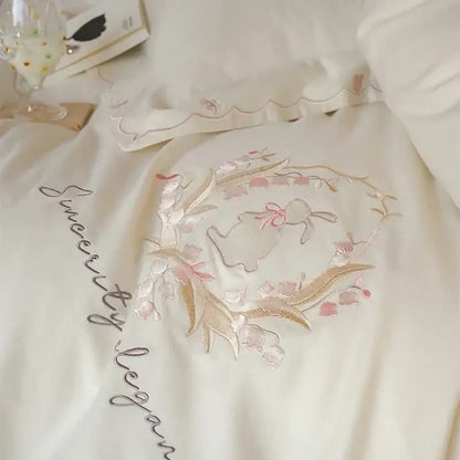 Cream satin pillowcase with gold and pink floral embroidery and central bunny motif in floral embroidered duvet cover set