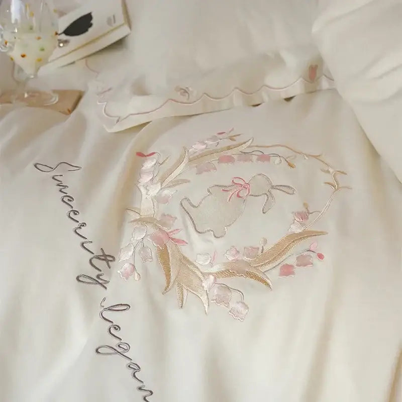 Cream satin pillowcase with gold and pink floral embroidery and central bunny motif in floral embroidered duvet cover set