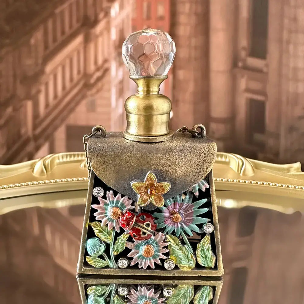 A half-moon-shaped enamel perfume bottle with brass base and crystal stopper in a metal handicraft collection