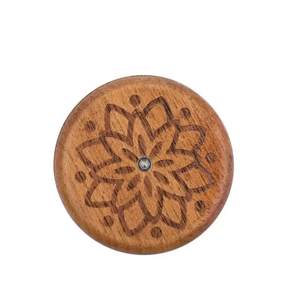 A round wooden french bread lame button with dark brown floral engraving and metallic center for bread lame dough scoring