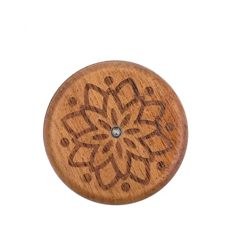 A round wooden french bread lame button with dark brown floral engraving and metallic center for bread lame dough scoring